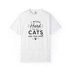 A white short-sleeve crewneck t-shirt with a black graphic text print that reads 'I WORK Hard SO MY CATS can live well.' with a small paw print underneath, displayed on a clean white background.