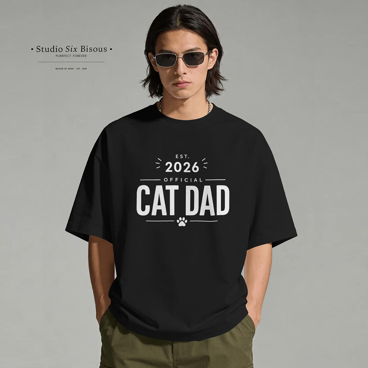 Person wearing a black t-shirt with 'Official Cat Dad 2026' text on a gray background