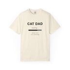 An off-white short-sleeve t-shirt with a black graphic print that reads 'CAT DAD' above a loading bar and the text 'please wait cat is deciding'.