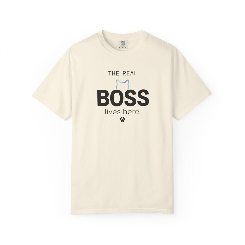 A cream-colored short-sleeve t-shirt with a graphic on the front that reads 'THE REAL BOSS lives here.' in black text, featuring a small blue and black cat outline and paw print.
