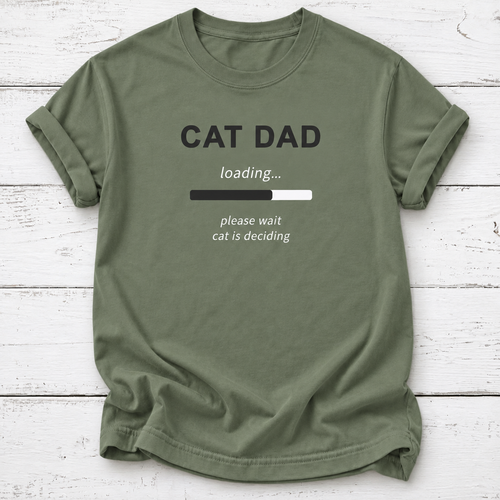 An olive green crewneck t-shirt with a 'CAT DAD' graphic print, laid flat on a white wood plank background.