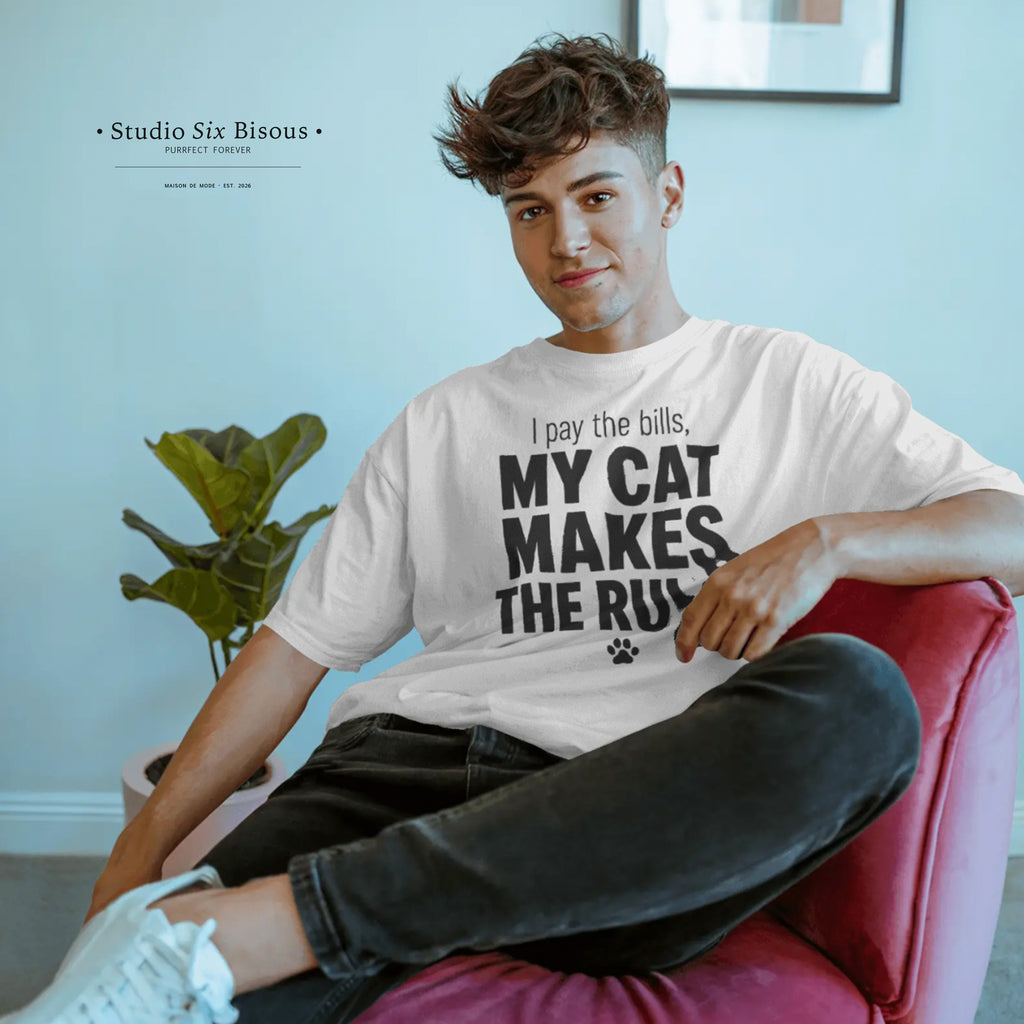 Person wearing a t-shirt with text sitting on a red chair in a room with a plant and framed picture.