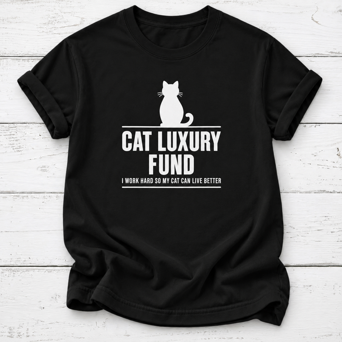 Black T-shirt with a white cat silhouette and “Cat Luxury Fund — I Work Hard So My Cat Can Live Better” lettering, laid flat on white wooden boards.