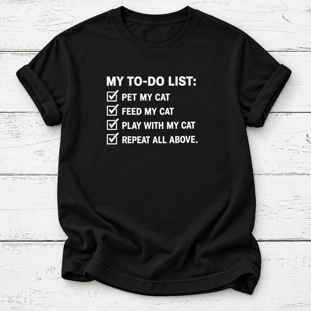 A black short-sleeve t-shirt with a white printed graphic that reads 'MY TO-DO LIST:' followed by four checked items: 'PET MY CAT', 'FEED MY CAT', 'PLAY WITH MY CAT', and 'REPEAT ALL ABOVE.' The shirt is laid flat on a white wood-plank background.