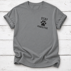 Gray T-shirt with a black paw print between “Stay” and “Pawsitive” on the left chest, with rolled sleeves, laid flat on white wooden board